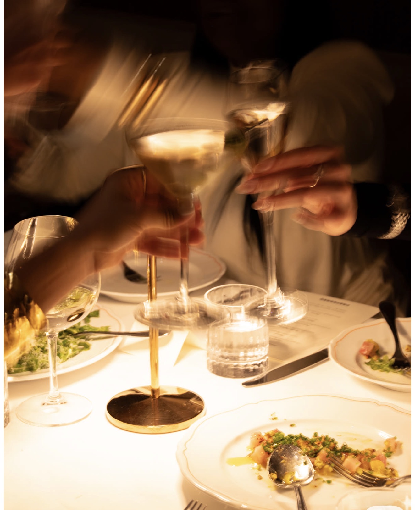 Candlelit dinner table, glasses raised in a toast